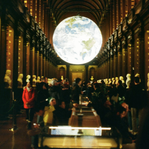An illuminated globe suspended indoors in a dark museum room.