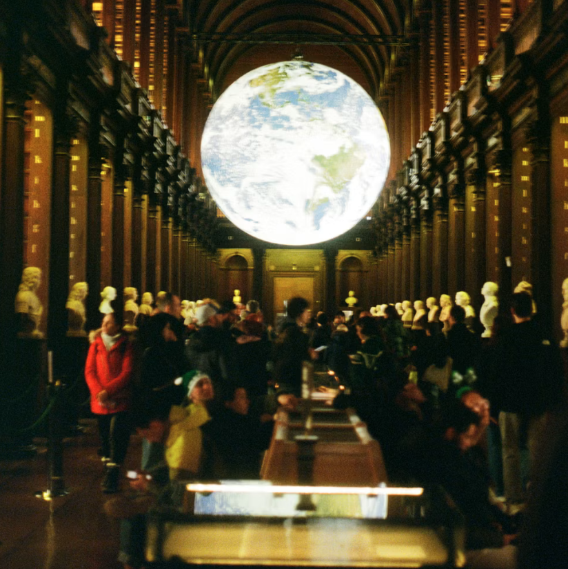 An illuminated globe suspended indoors in a dark museum room.