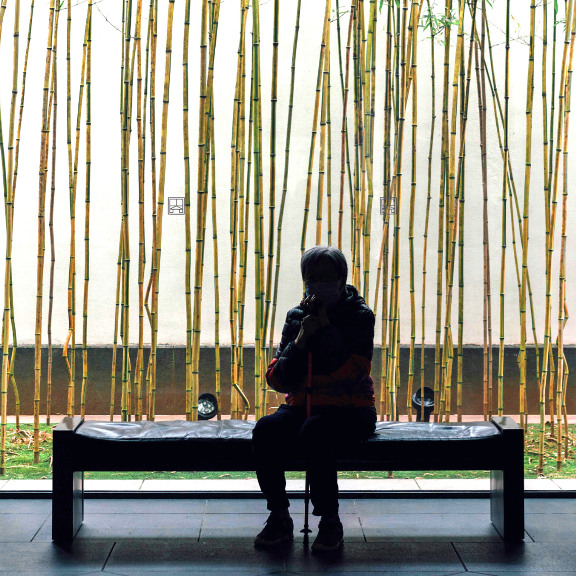 A woman sitting on a bench looking at an art installation of bamboo.