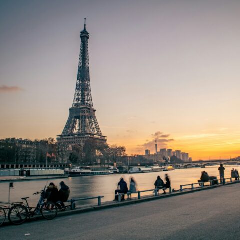 People sitting on benches with the Eiffel Tower in the background.