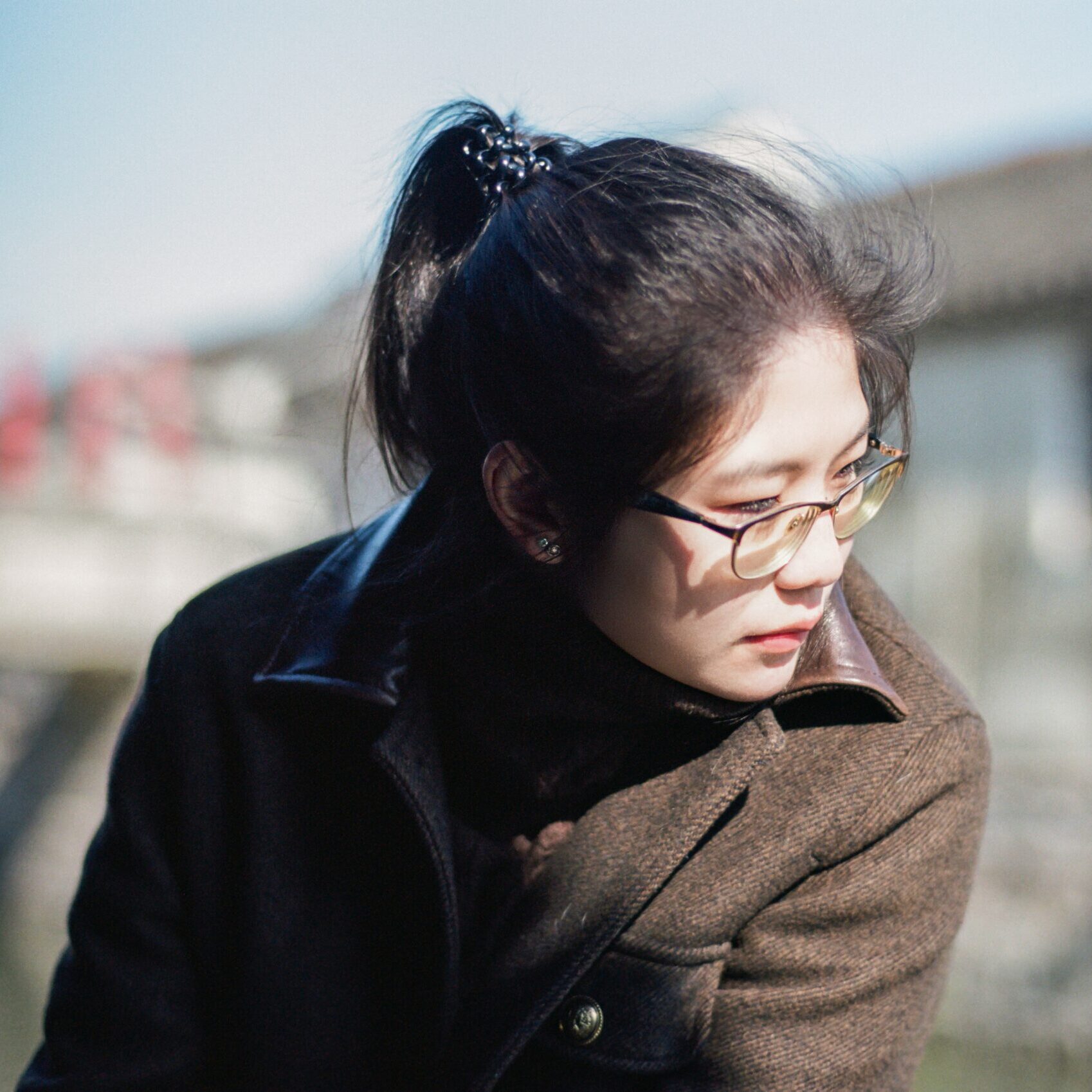 A woman wearing a brown coat and looking pensive.