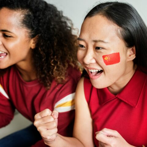 A young girl with a painted face cheering.