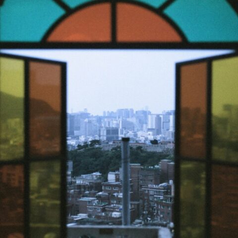 A stained glass window opening to a city view.