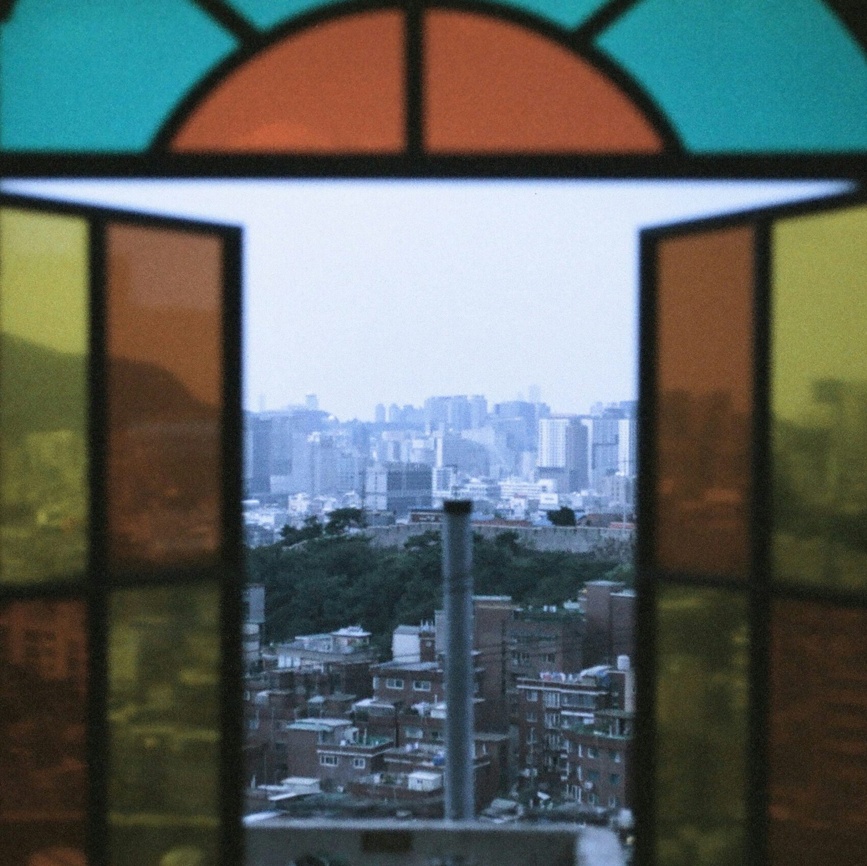 A stained glass window opening to a city view.