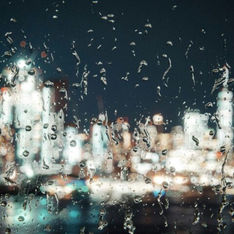 A blurred rainy night city scene seen through a window.