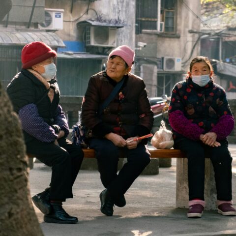 Three elderly women chatting on a park bench.